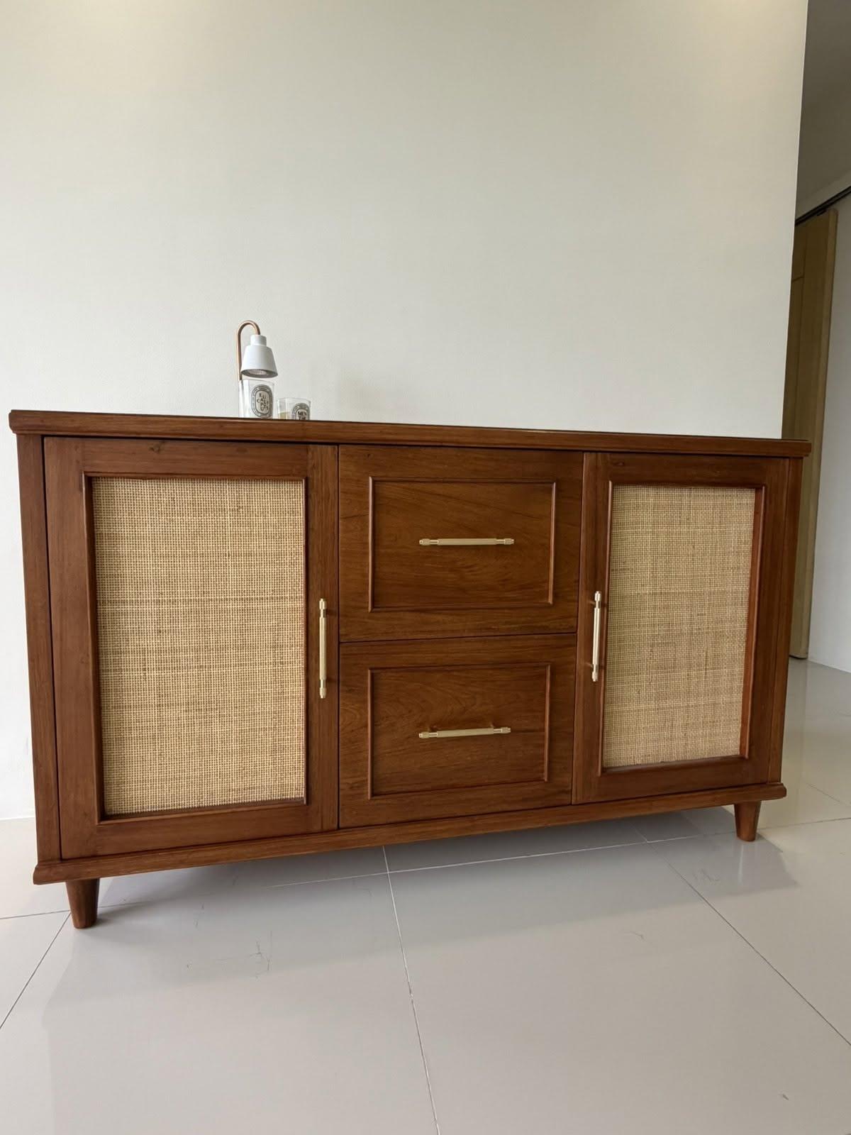 A cane-front wood storage cabinet in a home interior.