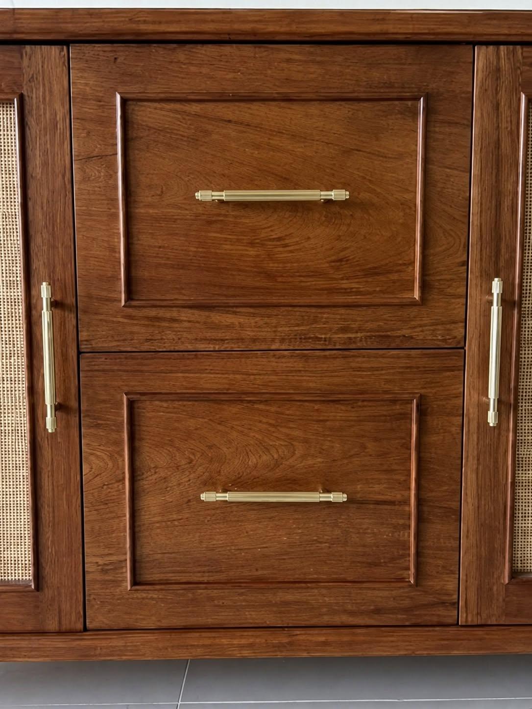 Wood drawer fronts with slender gold-coloured handles.